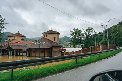 Road by buildings against sky