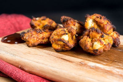 Close-up of roasted chicken wings on cutting board against black background