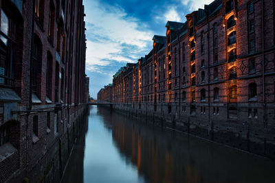 Canal amidst buildings against sky in city