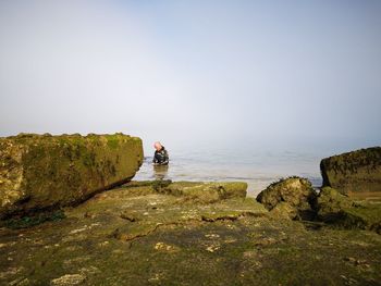 Man on rocks against clear sky