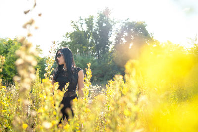 Young woman with yellow flowers on field