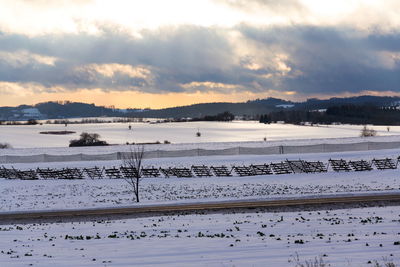 Scenic view of snow covered land against sky during sunset