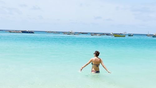 Full length of shirtless man on sea against sky