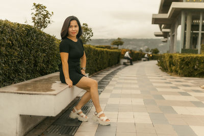 Portrait of young woman walking on footpath