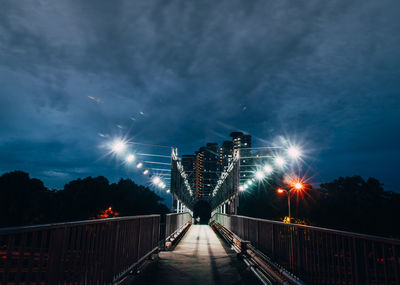 Low angle view of illuminated footbridge against sky at night