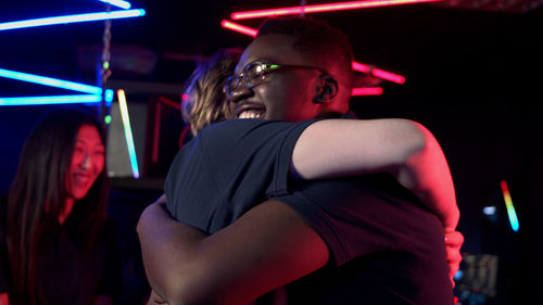 Cheerful friends hugging at internet cafe