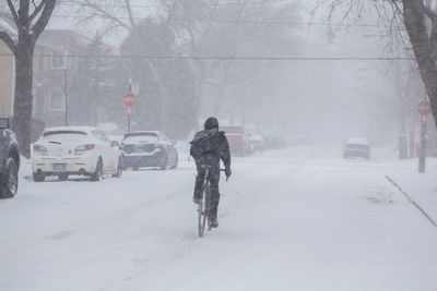 Rear view of man walking on snow covered road