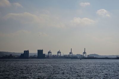 View of harbor cranes against cloudy sky