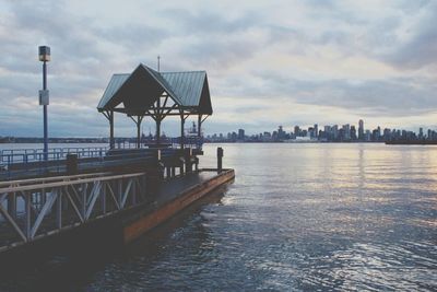 Pier in sea against cloudy sky