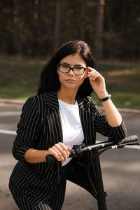 Woman wearing eyeglasses standing against trees