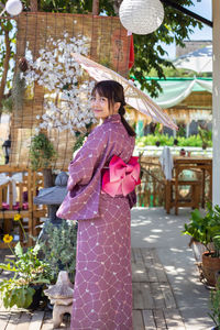 Portrait of woman standing by flowering plants outdoors