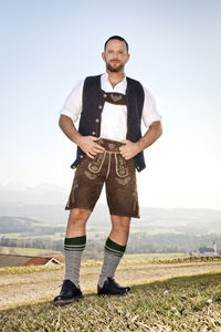 Portrait of man in costume standing on field against sky