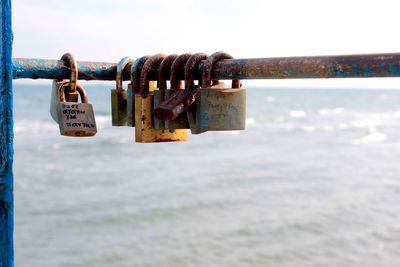 Close-up of padlocks on railing against sea