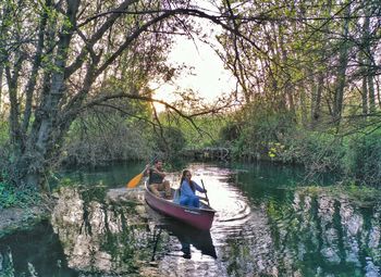 People sitting on boat in lake against trees in forest