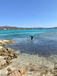 Rear view of man on beach against clear blue sky