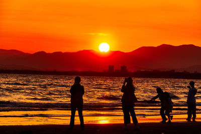 Silhouette couple at beach against sky during sunset