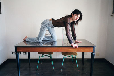 Young woman sitting on table at home