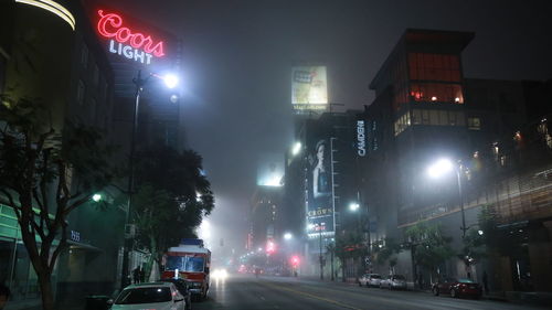 Cars on illuminated city street at night