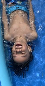 High angle portrait of smiling young woman swimming in pool