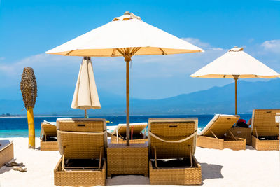 Lounge chairs and parasols at beach against sky