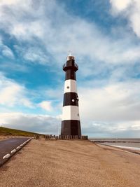 Lighthouse on landscape against sky