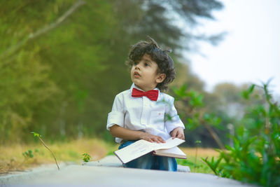 Boy looking away against trees