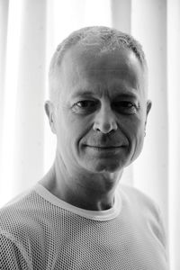 Close-up portrait of smiling man against curtain