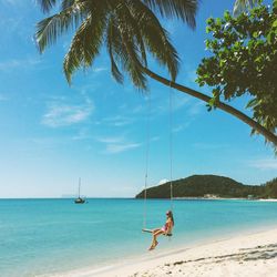 Woman on swing at calm beach