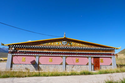 Temple against building against clear blue sky