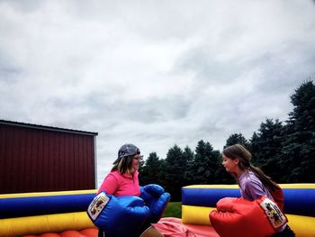 Rear view of people sitting on seat against sky