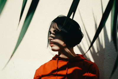 Portrait of young woman standing against wall