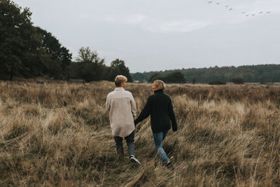 Rear view of couple walking on field