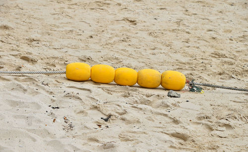 High angle view of yellow buoys and rope on sand at beach