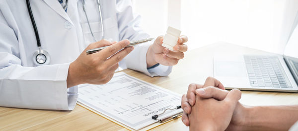 Midsection of doctor working on table