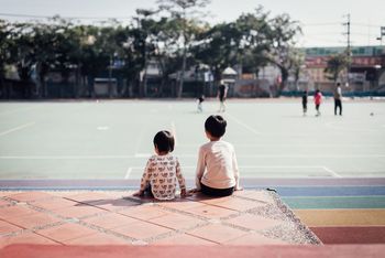 Rear view of siblings sitting at playground