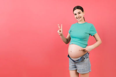 Portrait of a smiling young woman against pink background