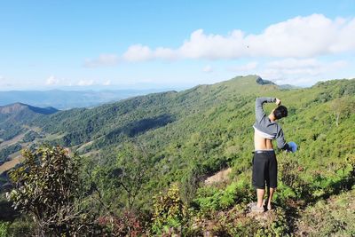 Rear view of woman standing on mountain against sky