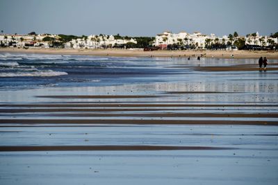 Scenic view of beach by city against sky