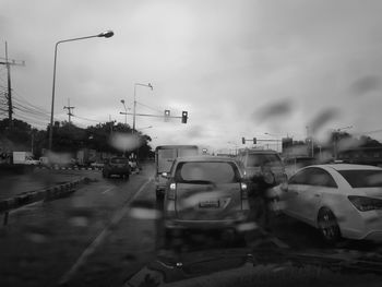 Vehicles on road against cloudy sky