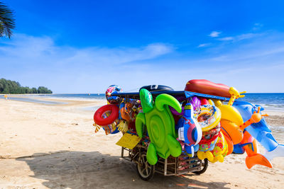 Colorful toys on truck at beach against blue sky