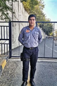 Portrait of young man standing against railing