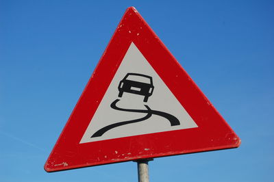 Close-up of road sign against clear blue sky