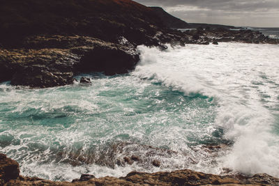 View of waves breaking against sea