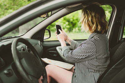Midsection of woman using mobile phone while sitting in car