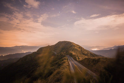 Scenic view of mountain road against cloudy sky