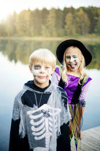 Portrait of smiling git standing against lake in halloween costume 