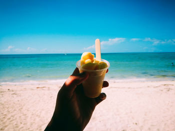 Midsection of person holding ice cream on beach