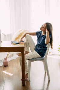 A high school student sits at home at her desk, takes a break before preparing for classes or exams