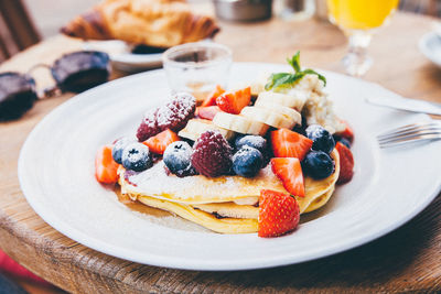 Close-up of pancake with fruits in plate on table