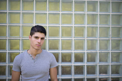 Portrait of young man standing by wall outdoors